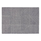 A rectangular area rug with a modern geometric pattern of gray and white blocks, lines, and triangles, shown flat against a white background.