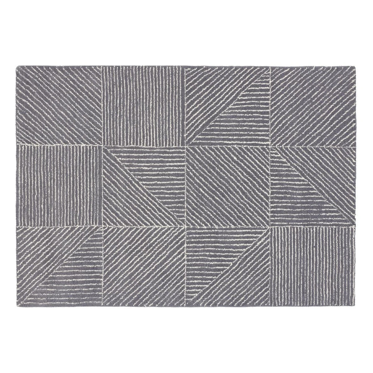 A rectangular area rug with a modern geometric pattern of gray and white blocks, lines, and triangles, shown flat against a white background.