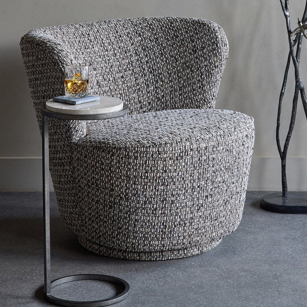 Gray textured armchair with a small round table on a gray floor.